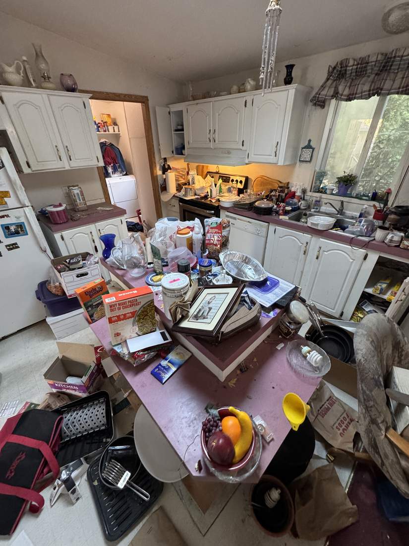 A kitchen full of belongings, dishes, and personal items before an estate cleanout