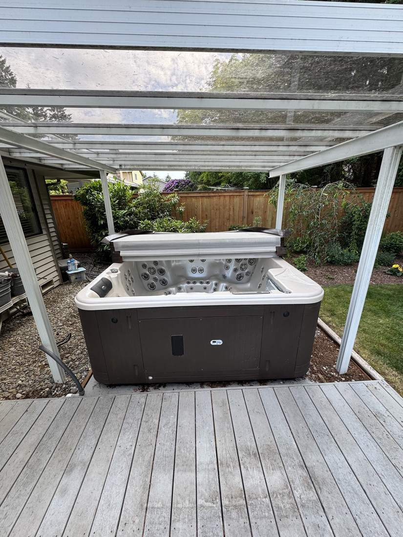 An intact hot tub on a backyard deck before removal